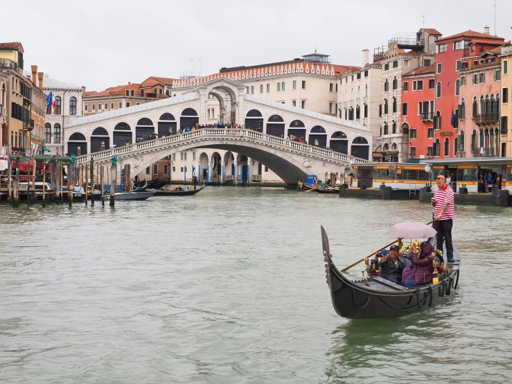 a person in a gondola near a bridge and buildings