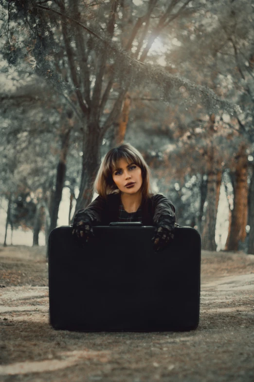 a woman is sitting on the grass holding a briefcase