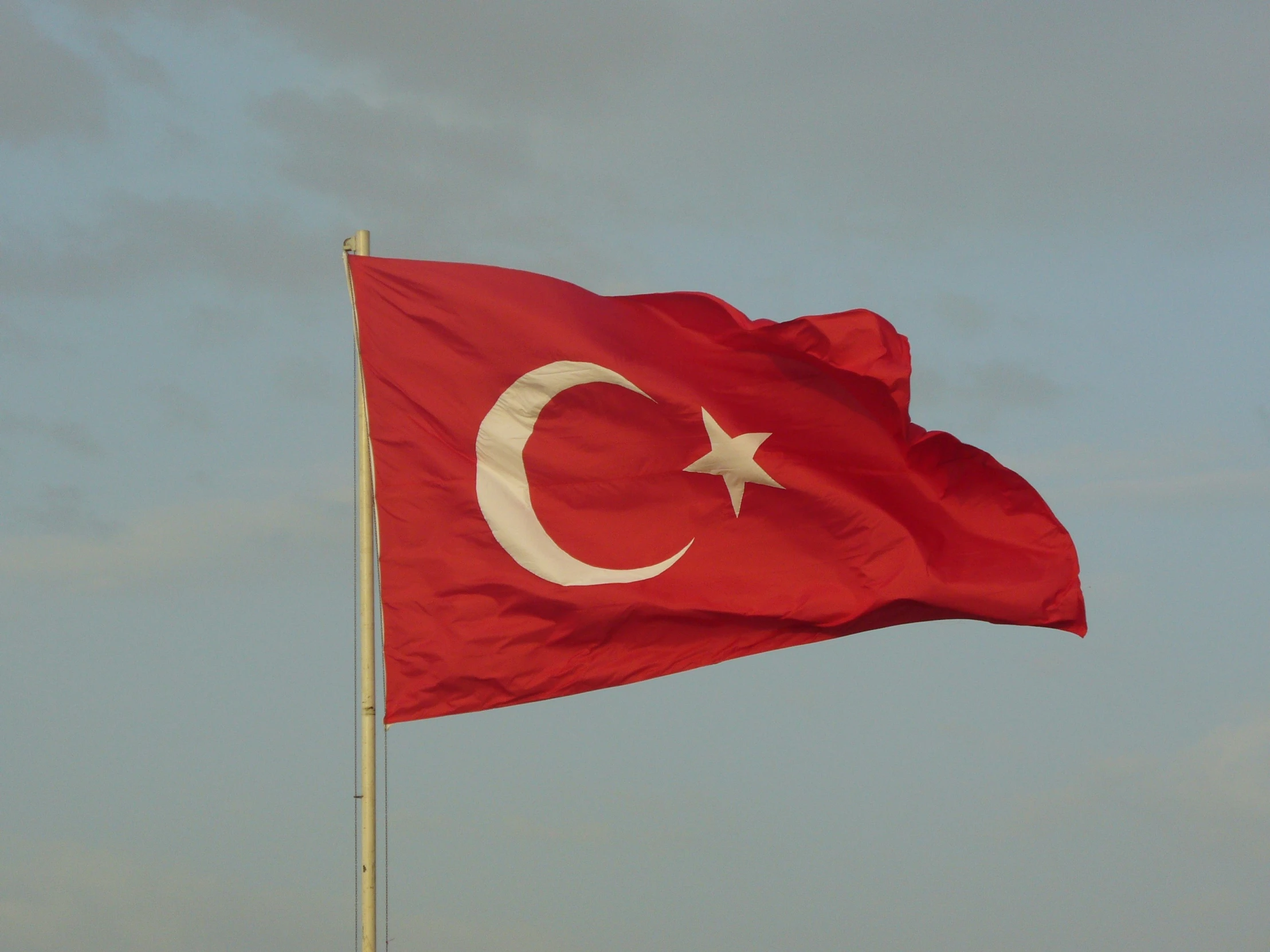 the large turkey flag is flying in the sky