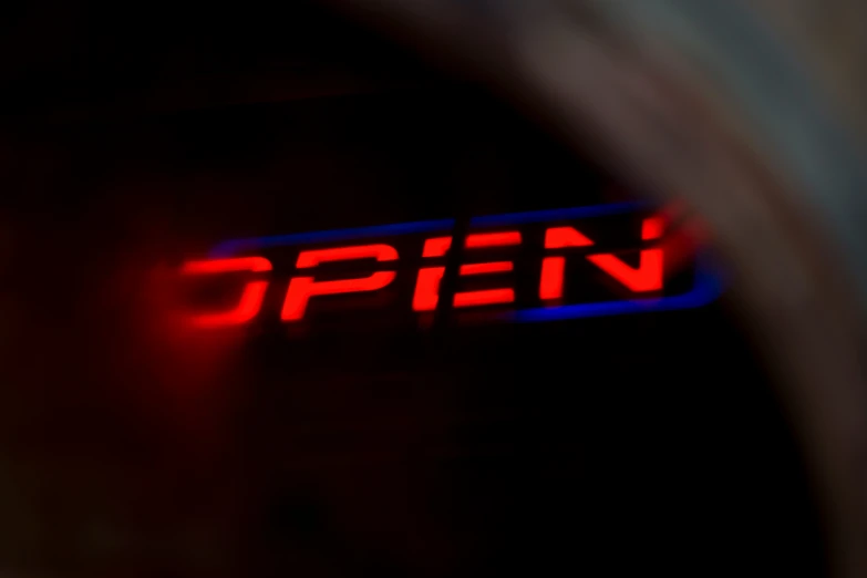 a black tunnel with a red neon open sign on the door