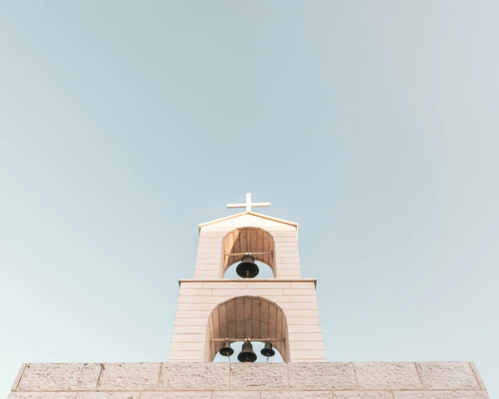 a cross atop a brick building on a sunny day