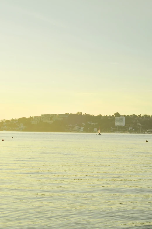 a lake and sailboat near a city at dusk