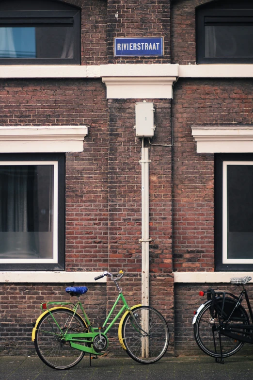 two bikes sitting next to each other against a brick building