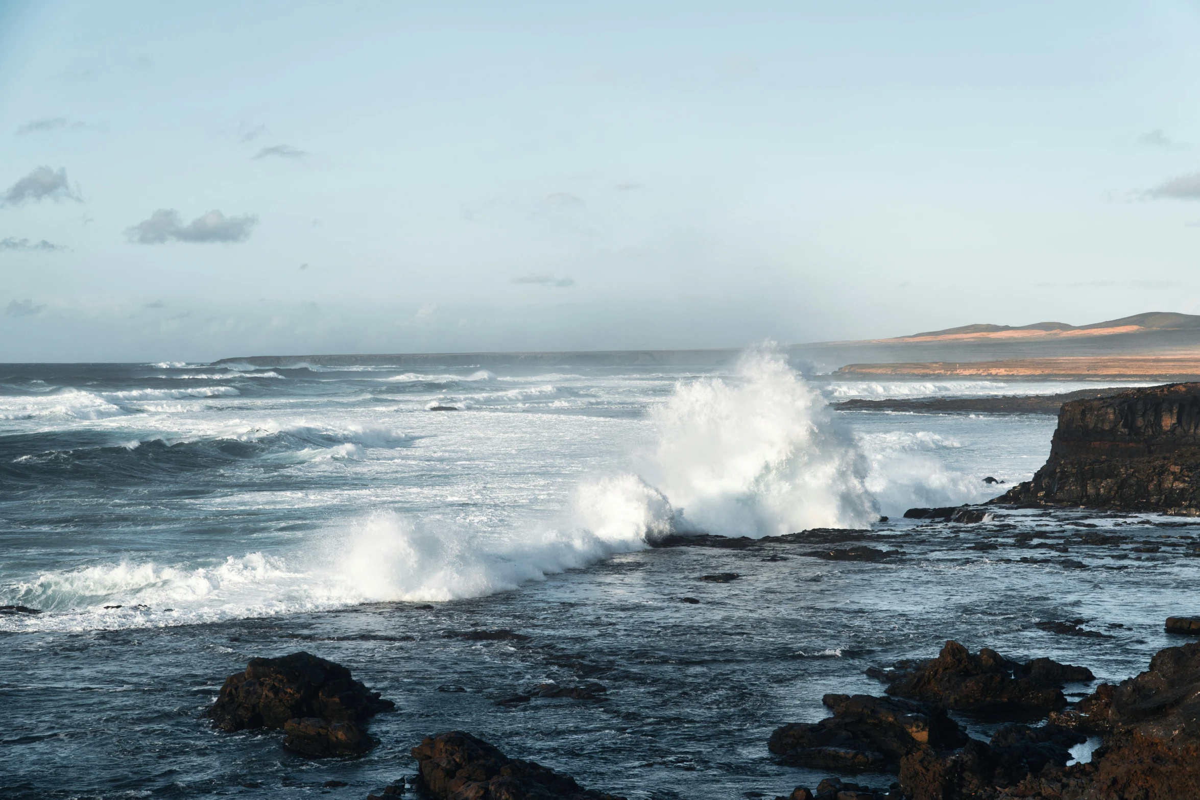 a big wave hitting against the shore and water splashing around