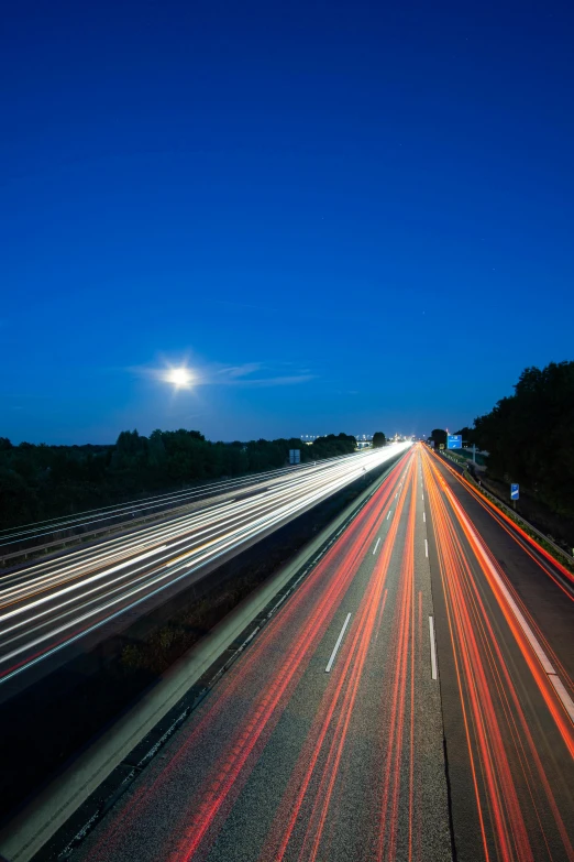 a freeway at night with a full moon and stars above