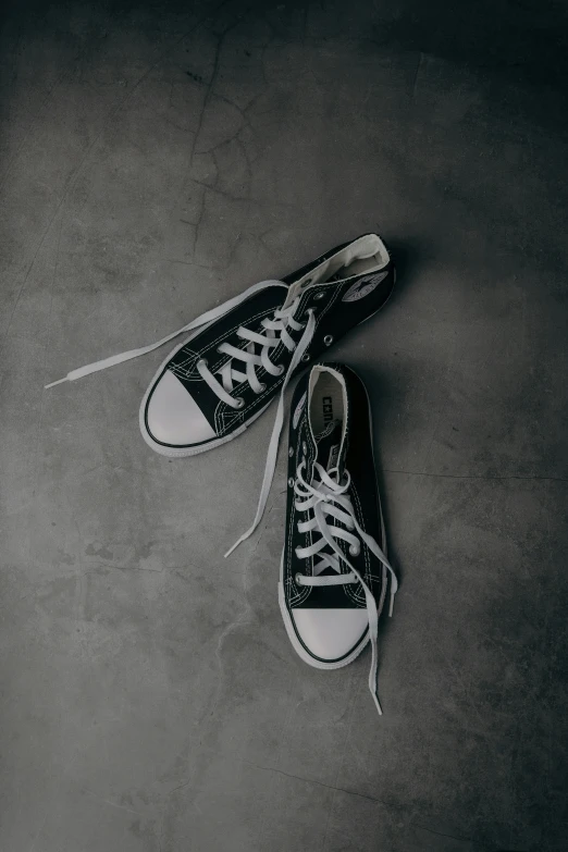 a black pair of converse shoes that are on the ground