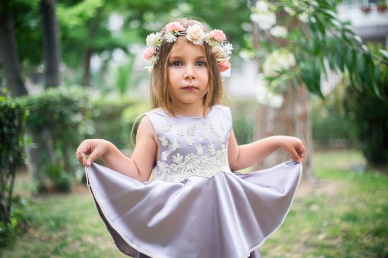 little girl in a flower crown sits on the back of her dress