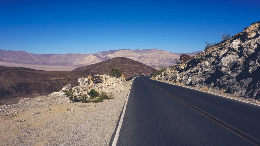an open road next to a mountain in the desert