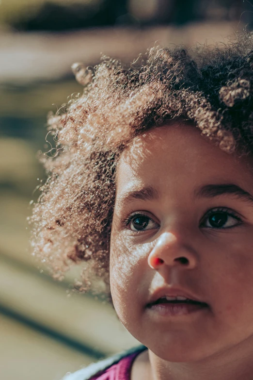 a little girl with curly hair wearing a necklace