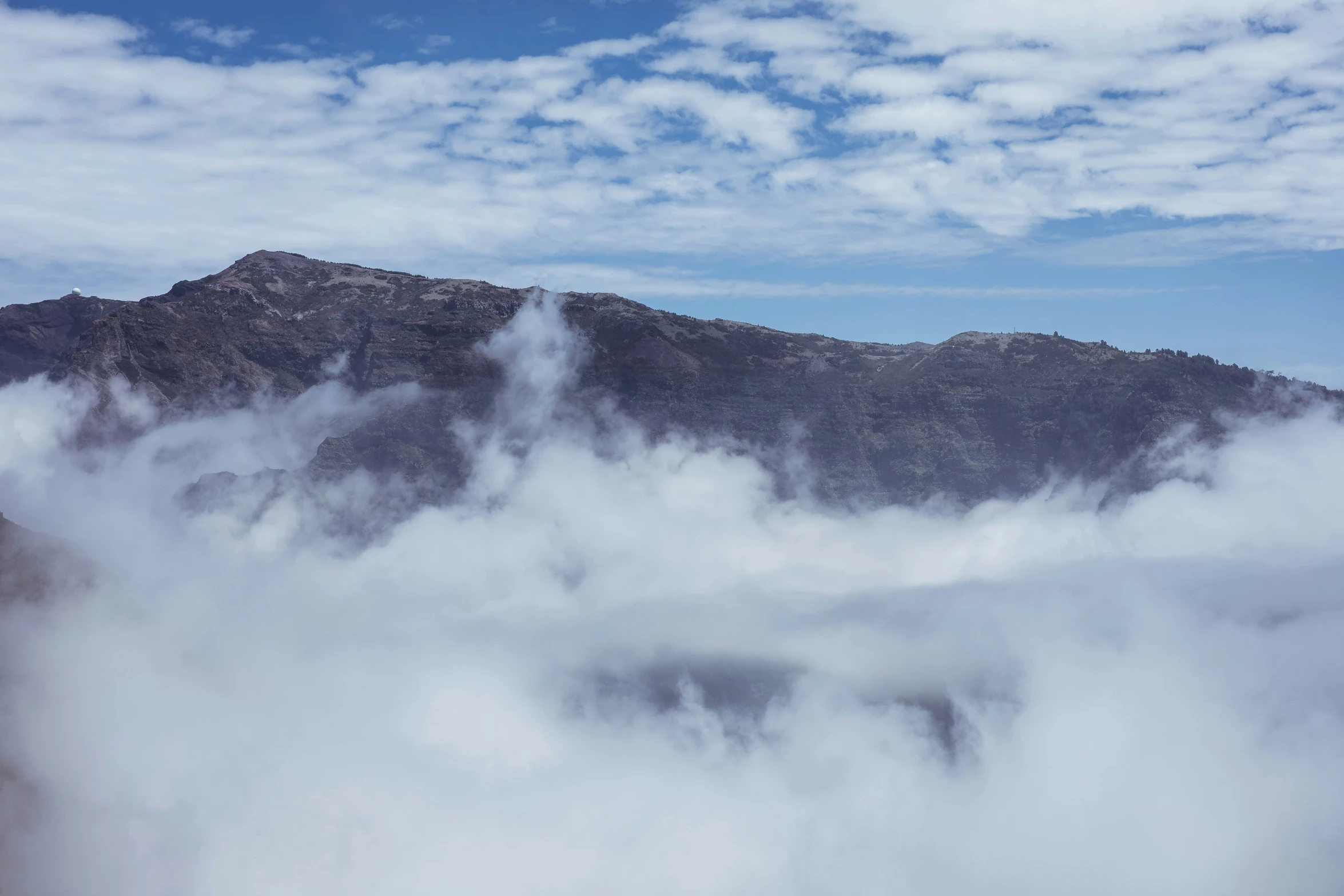 low clouds billow out the mountains beneath