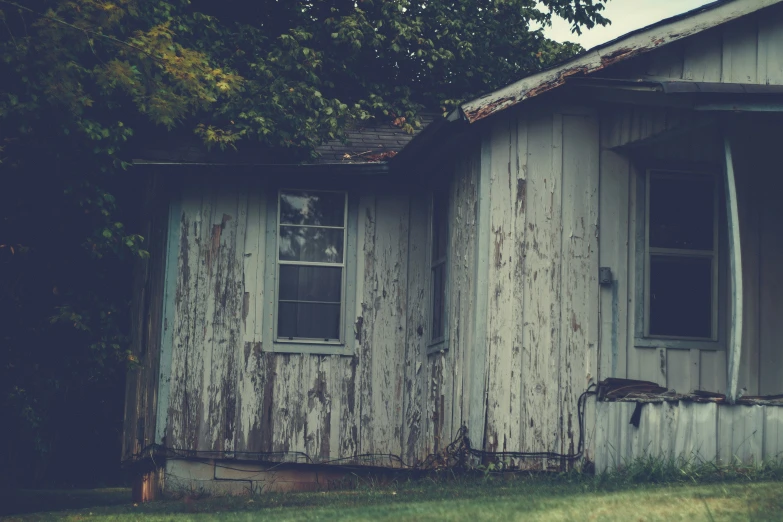 an old, rustic wooden house in front of a tree