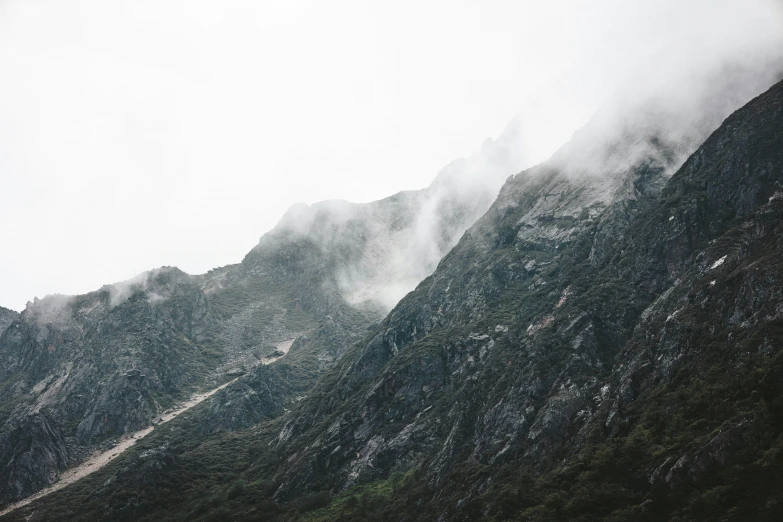 mountains with mist hovering on top are in the clouds