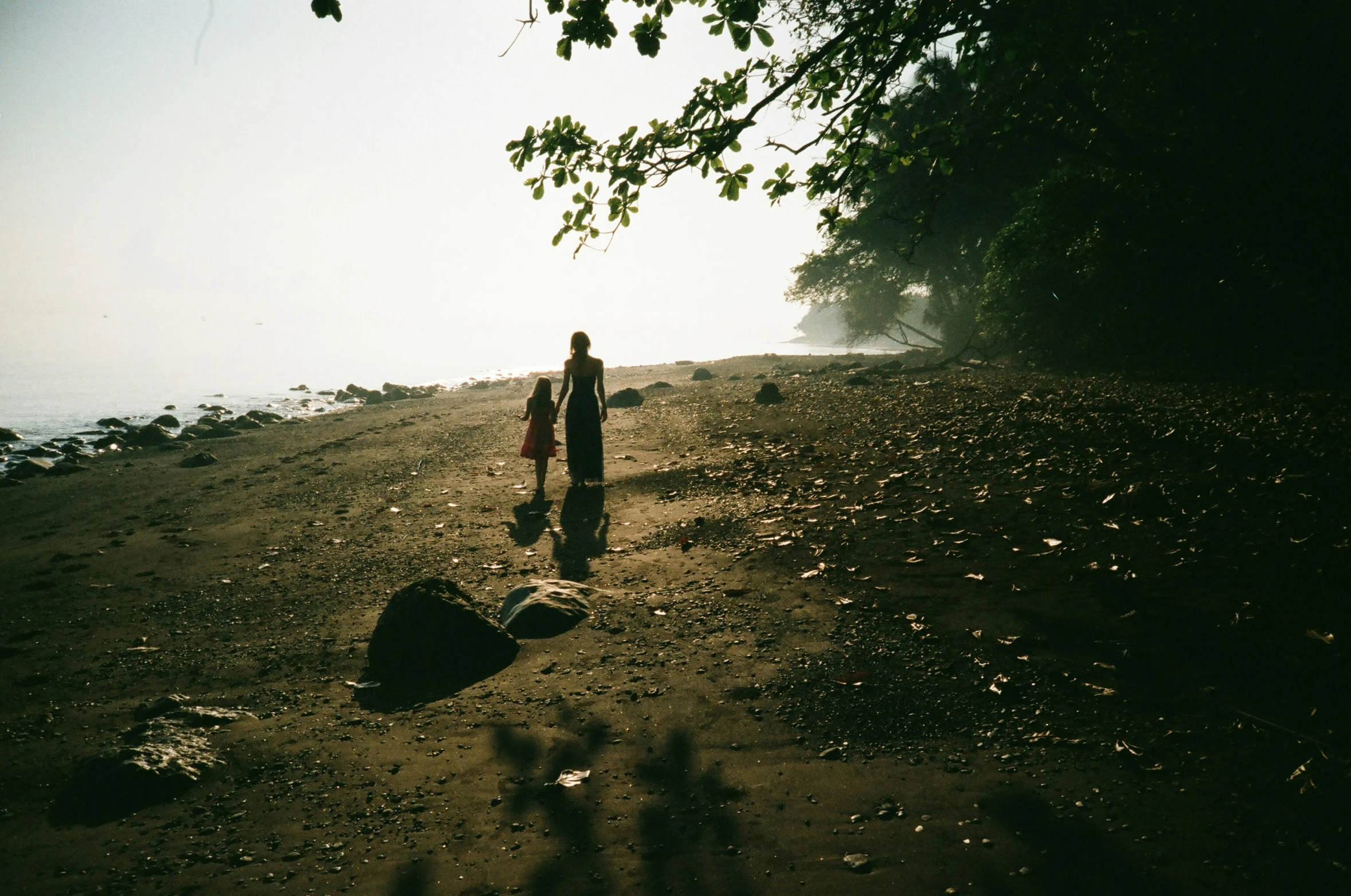 two people standing on a hill near the water