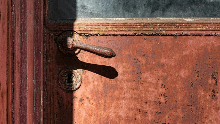 an old rusted wooden door handle on a red and gray door