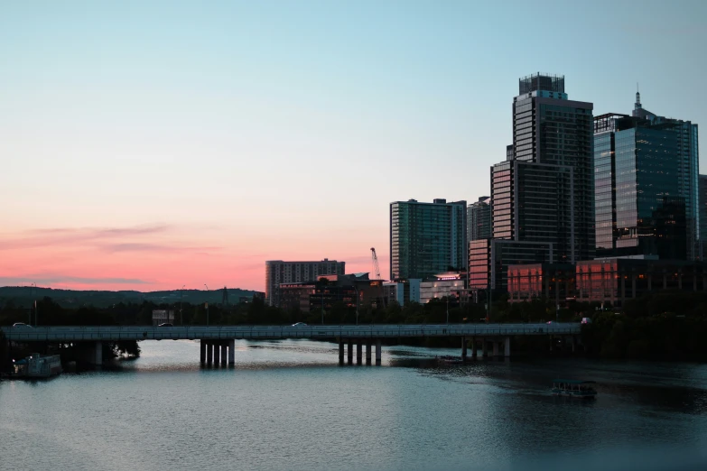 a bridge across the river with many tall buildings behind it