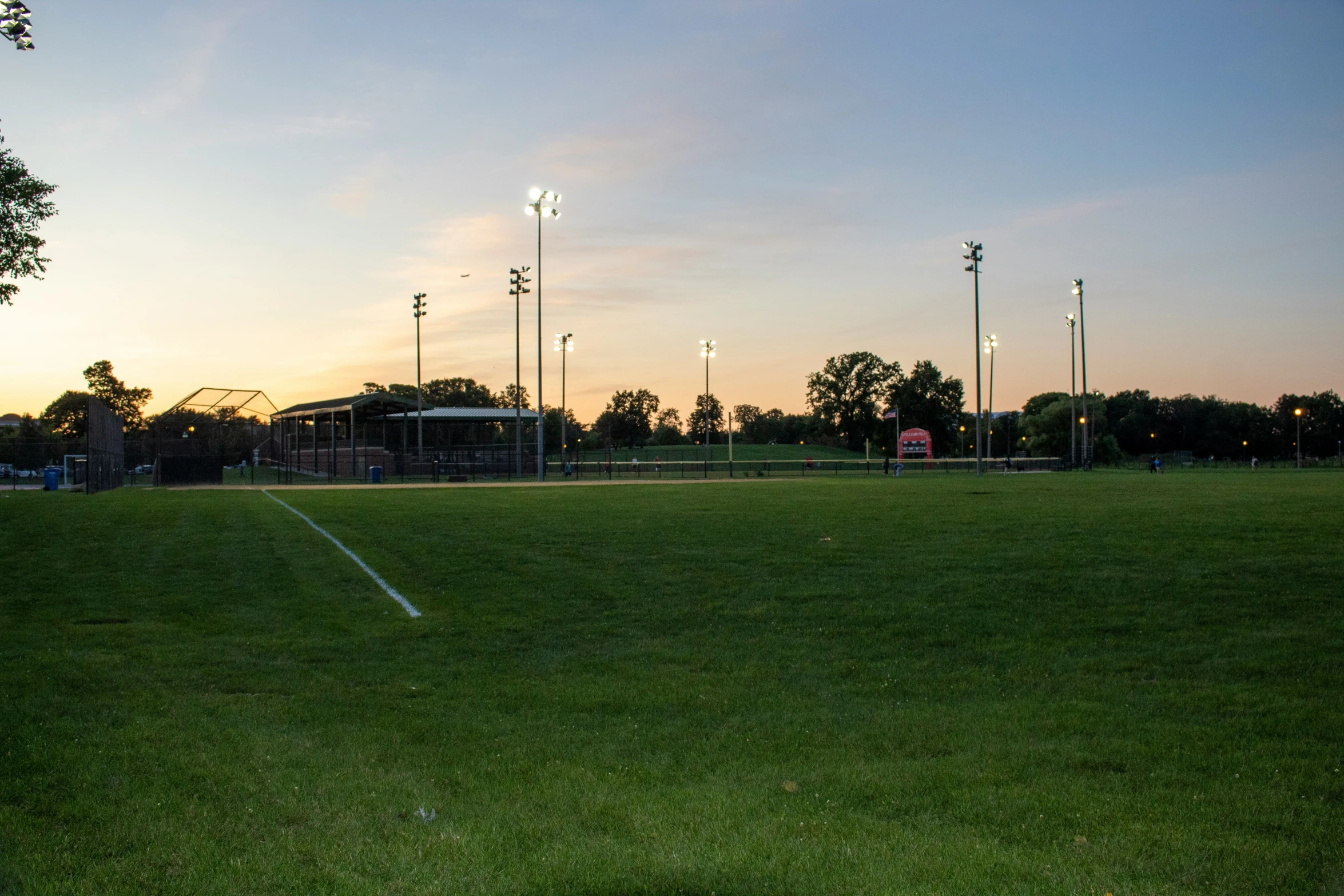 a green soccer field with lights on during a dusk