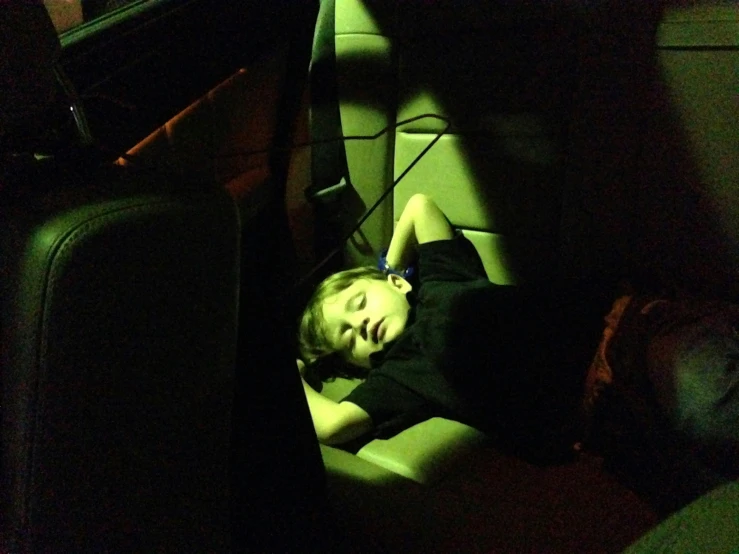 a woman sleeps inside a car with the passenger back and head down