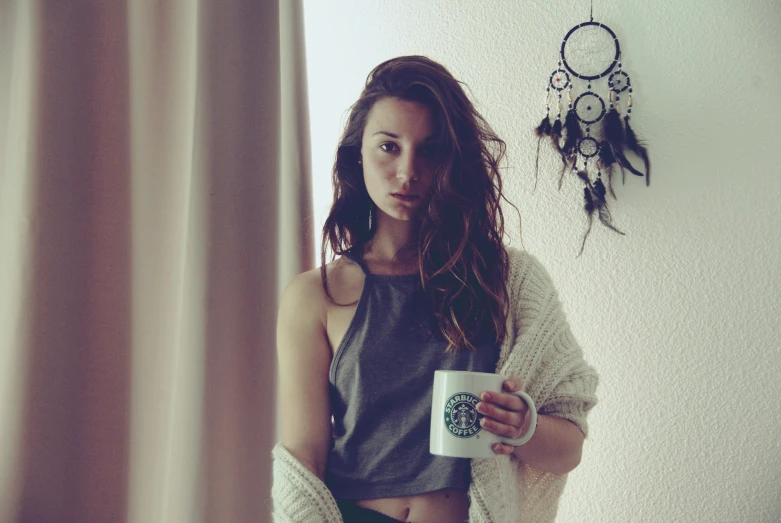 a girl with a cup of coffee looks out the window
