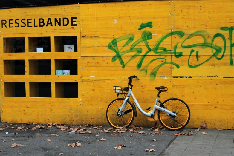a bicycle parked against a yellow wall with graffiti