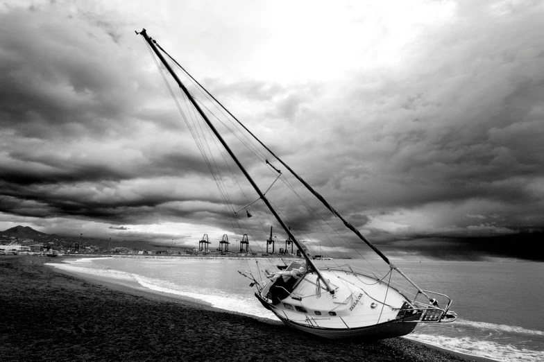 a boat sits on the beach with a storm coming in