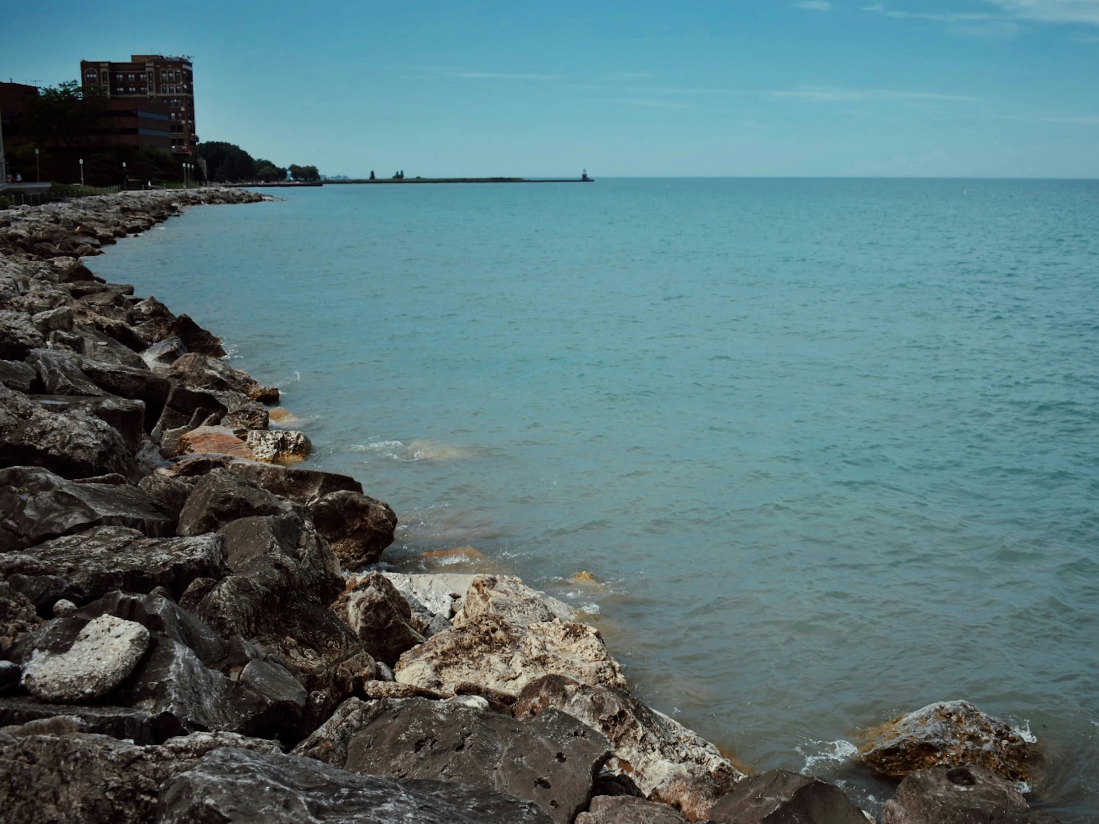 a rocky shore line on the water is seen from a distance