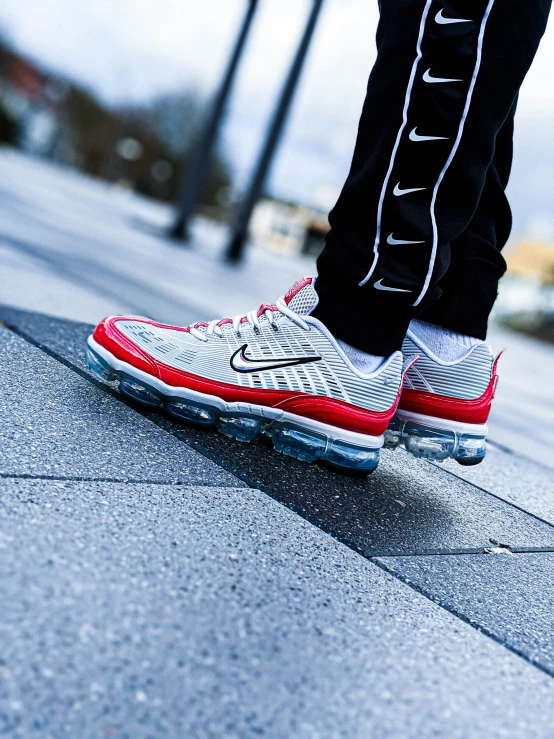 man in white sneakers walking on street next to pole