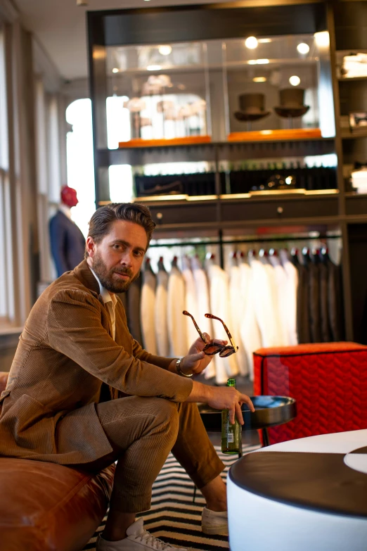 a man holds an object while sitting in front of a rack with clothes