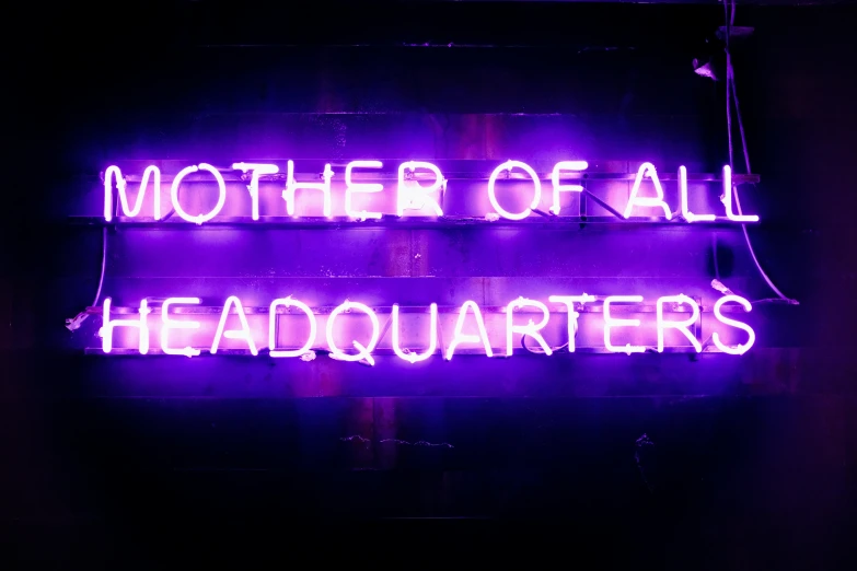 this neon sign has purple lights that reads, mother of all headquarters