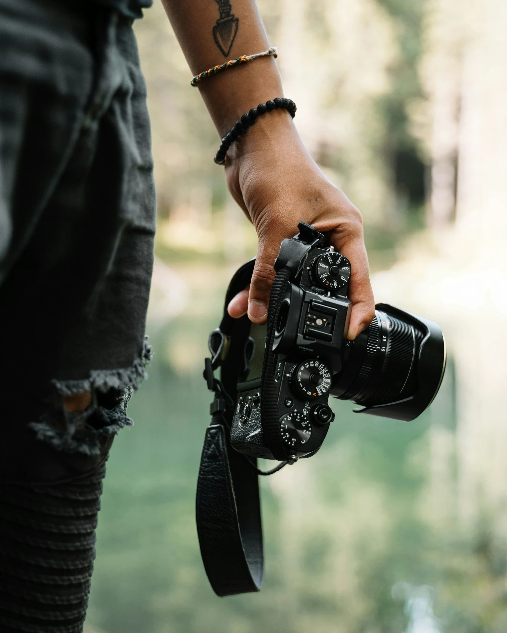 hand holding a camera with water in the background