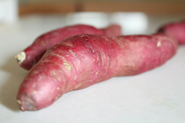 three large purple sweet potatoes sitting on top of a counter