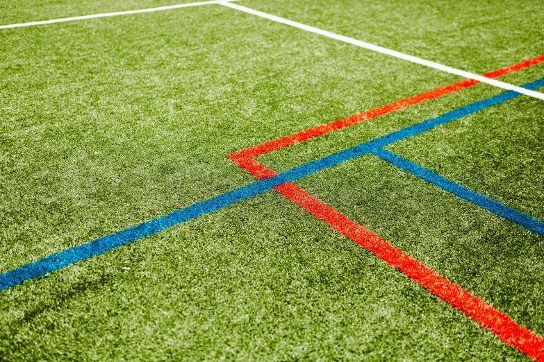 a red and blue tennis court line with grass