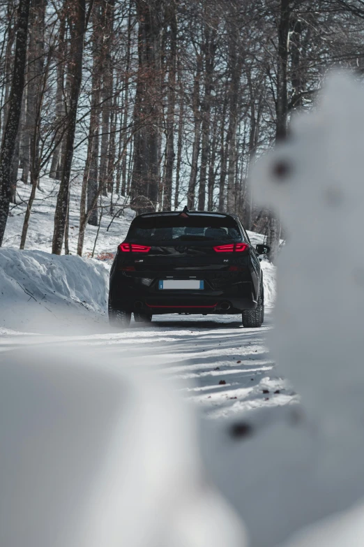 a car driving down the road in a snowy forest