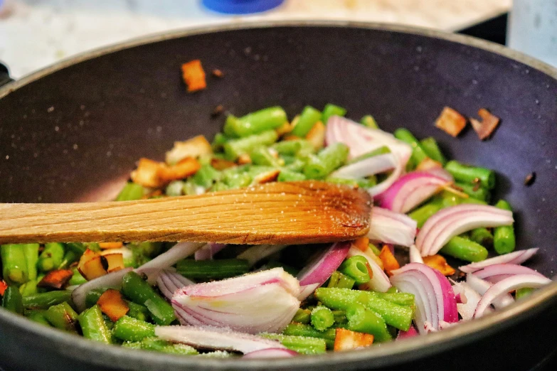 chopped onions, carrots and snap peas cooking in a wok