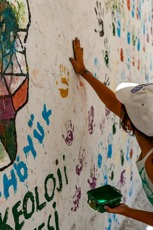 a young person writing on a wall in front of hand prints