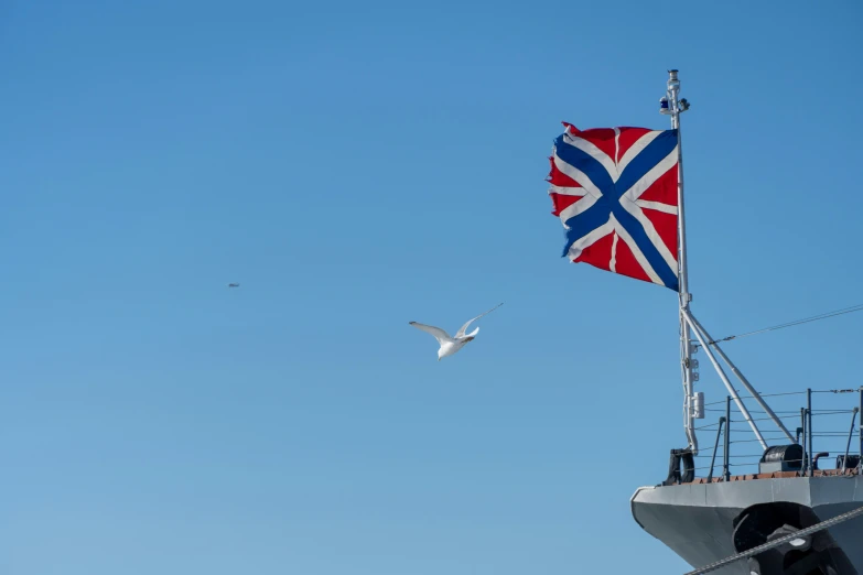 two white birds are flying near the british flag