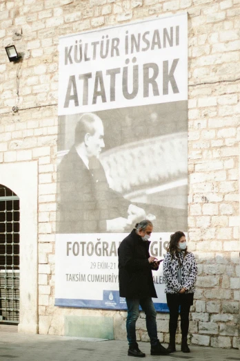 two people stand outside next to a building advertising an image of a man and woman