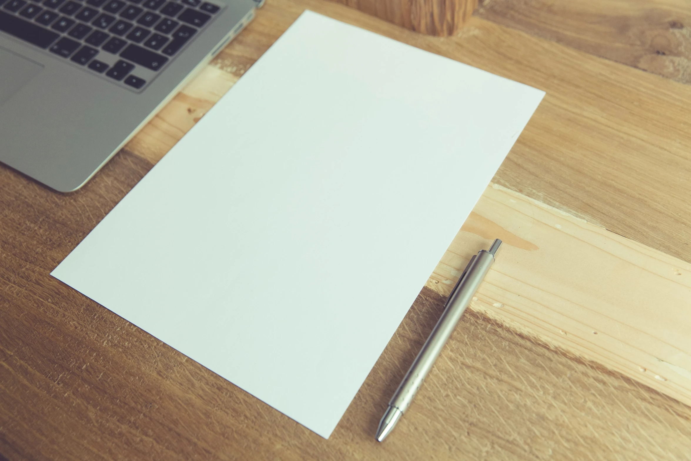 a pen and a laptop on a wooden desk