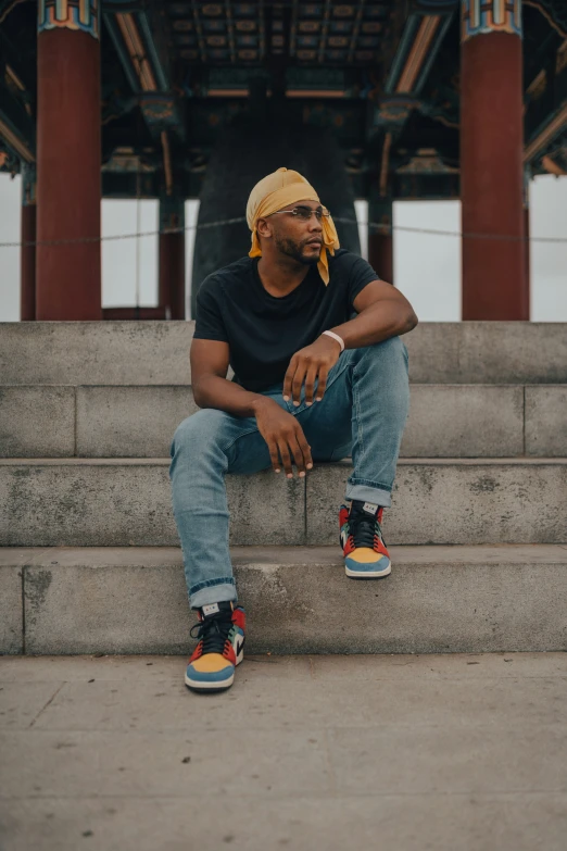 a man with yellow wig and yellow sneakers sits on stairs