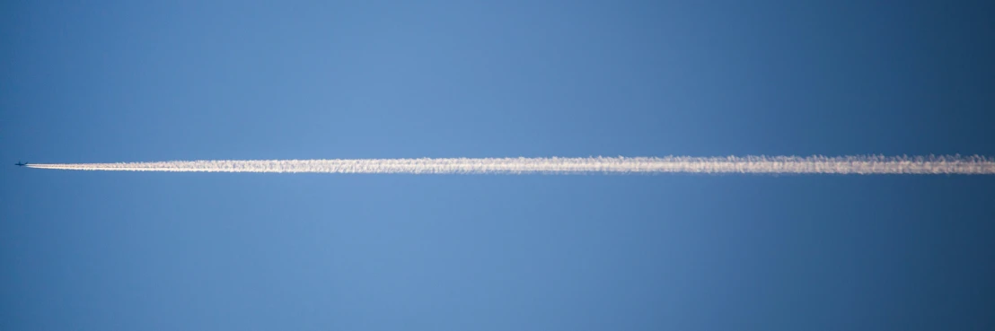 a contrail flying across the blue sky