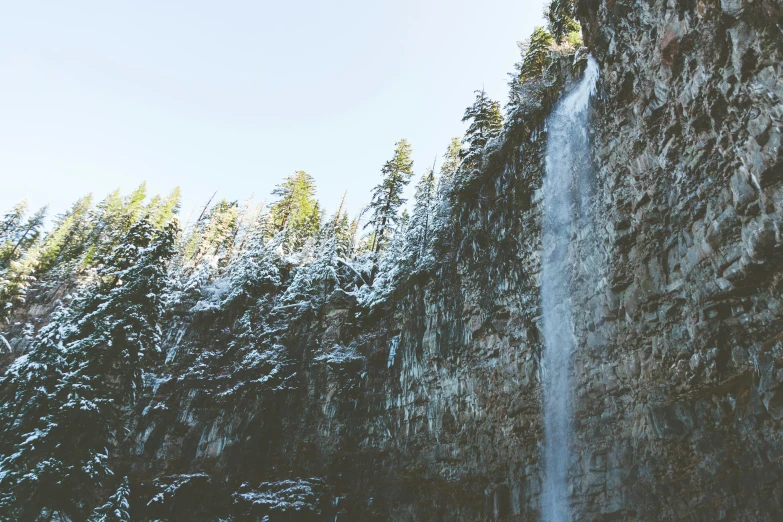 a water fall near a forested mountain side