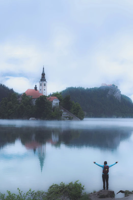 a person that is holding hands up by the water