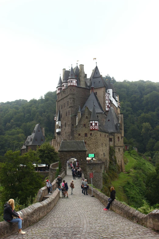 the castle on top of the mountain has many people standing around
