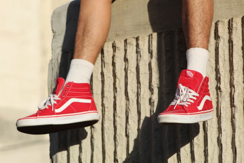 a person's legs in red and white tennis shoes