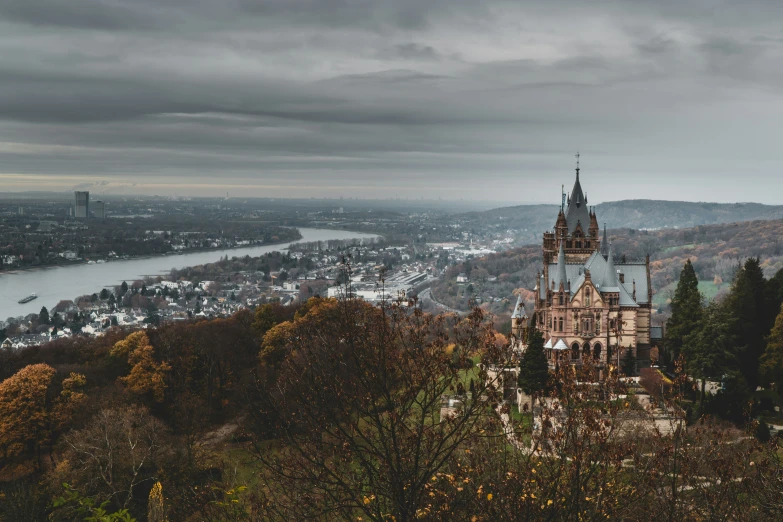 view of an old church in a valley, with buildings, trees, and buildings under dark clouds