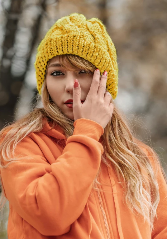 woman in orange jacket holding up her right hand to the side