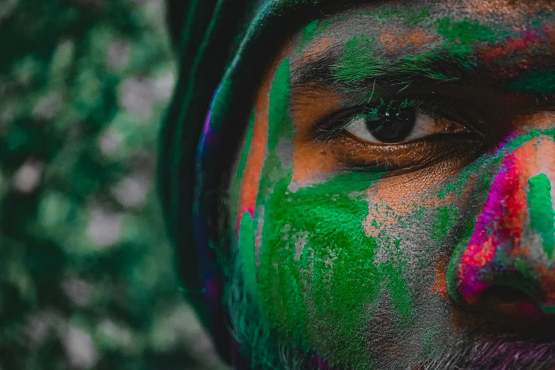 man with painted face and hood looking down