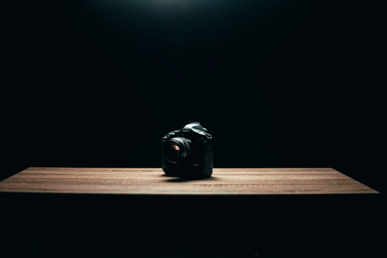a camera on a wooden table, in a dim room
