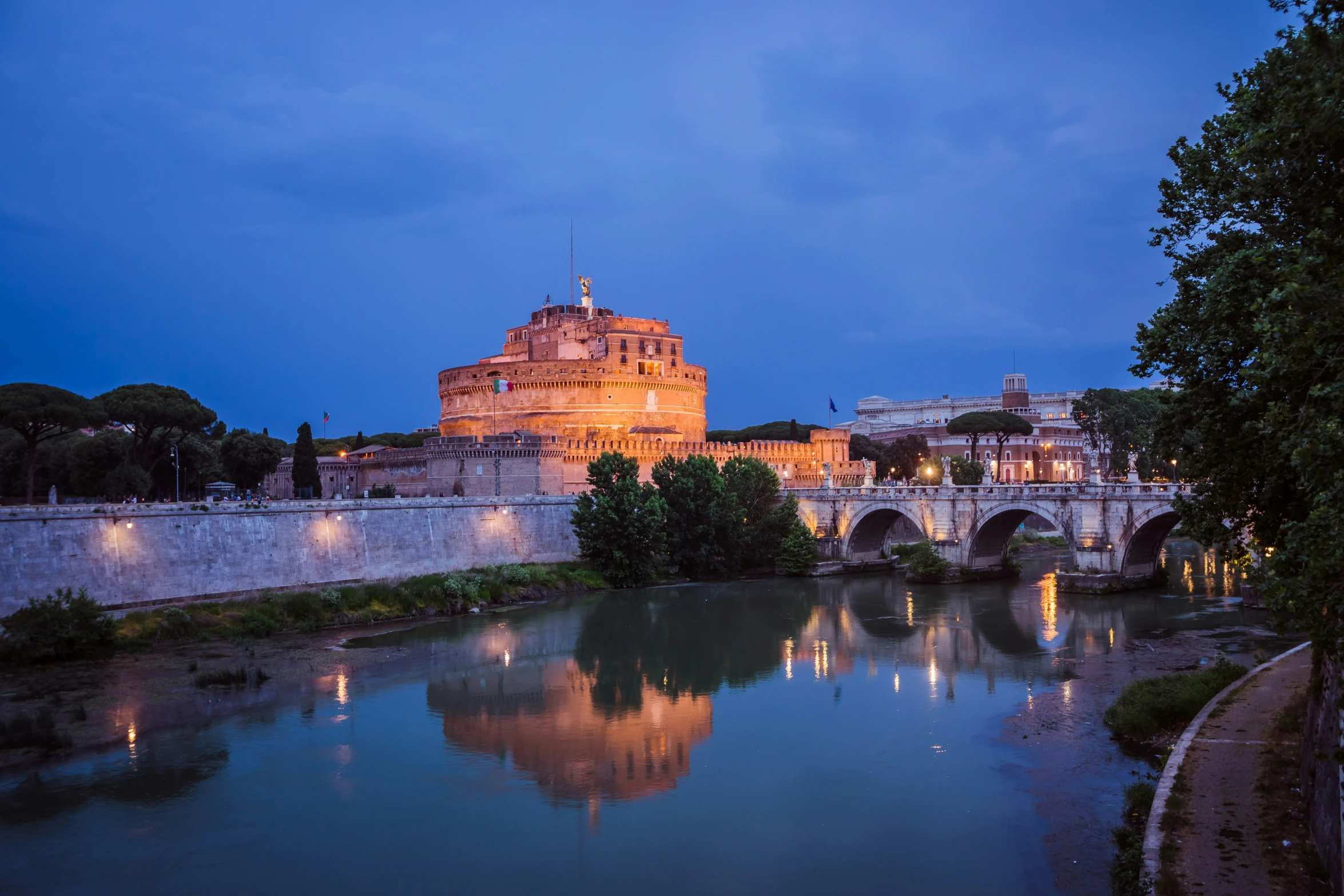 an illuminated castle stands on top of a mountain above a body of water