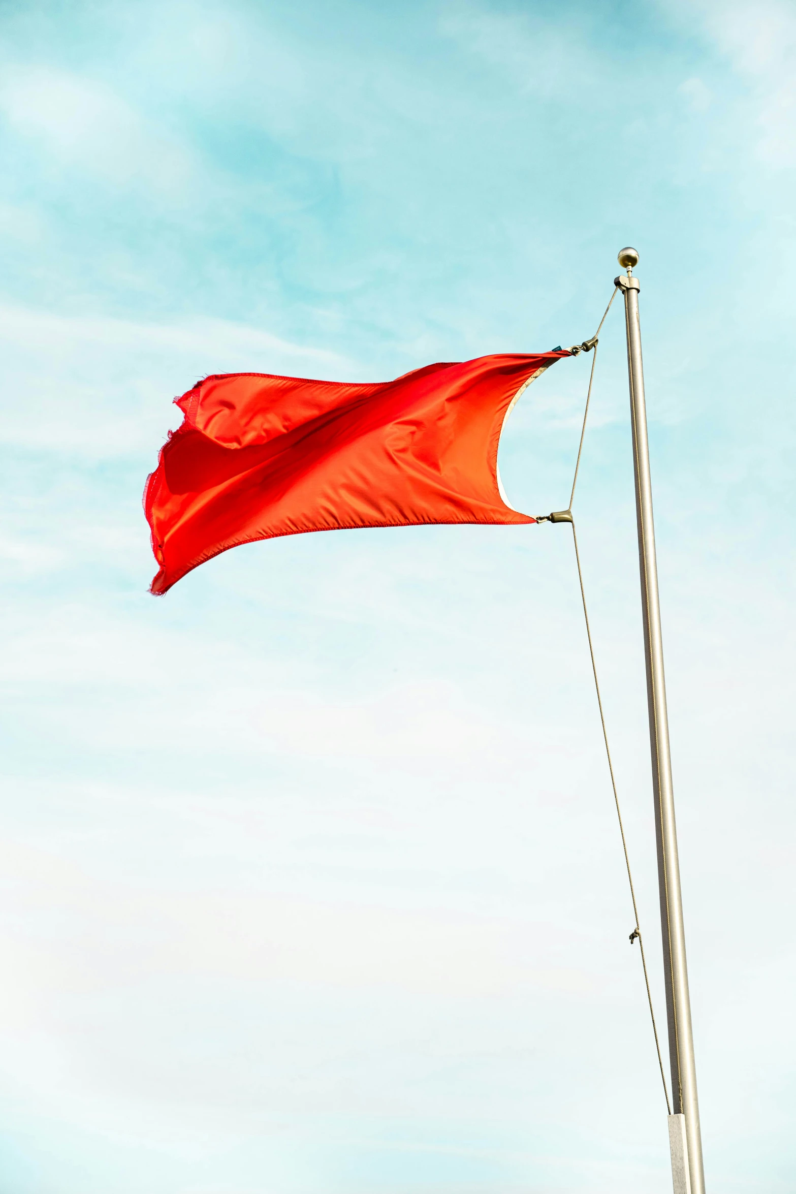 the red flag is sticking in front of a cloudless sky