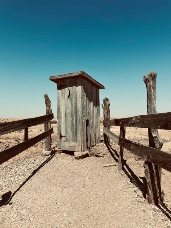 a small wooden outhouse sitting in the middle of the desert